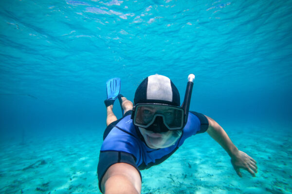 Freediver young man taking selfie portrait underwater, point of view.